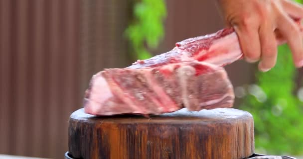Ένας άντρας κόβει ωμό κρέας σε ένα τετράγωνο με μαχαίρι. Νωπό κρέας σε ξύλο κοπής. — Αρχείο Βίντεο