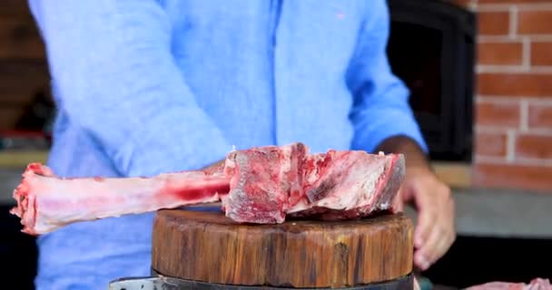 한 남자가 한 블록에서 칼로 날고기를 씹는다. 도마 위에 놓인 신선 한 고기. — 비디오