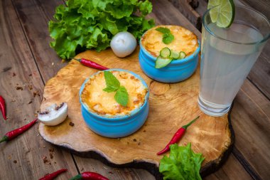 Ahşap bir tahtanın üzerinde mantarlı jülyen kaplar, otlarla süslenmiş. Julienne hindistan cevizli ve sarı peynirli..