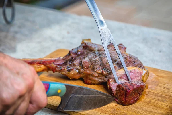 一个人在切菜板上切煎好的肉 烤肉当晚餐 后续行动 — 图库照片