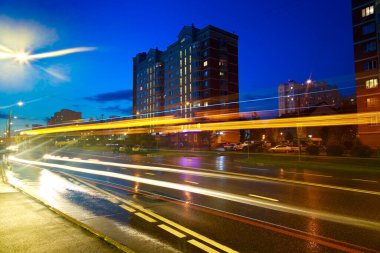 Gece şehrinin ışıklarının en üst görüntüsü. Batan güneş, alacakaranlık. Hareket halindeki arabalardan ışık izleri..