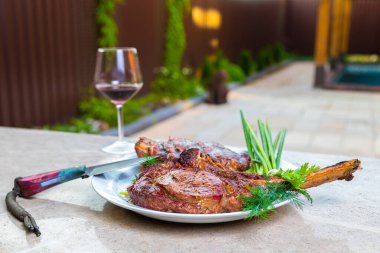 Beyaz tabakta baharatlı kızarmış et. Akşam yemeği için fırında et ve bir bardak kırmızı şarap. Yakın plan.