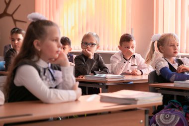 Çocuklar 1 Eylül 'de sınıfta masalarında otururlar. Birinci sınıflar ilk derste öğretmeni dikkatle dinlerler. Moskova, Rusya, 2 Eylül 2019