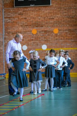 Spor salonundaki ilk beden eğitimi dersinde birinci sınıflar. Öğretmen öğrencilere bir görev verir. Moskova, Rusya, 2 Eylül 2019
