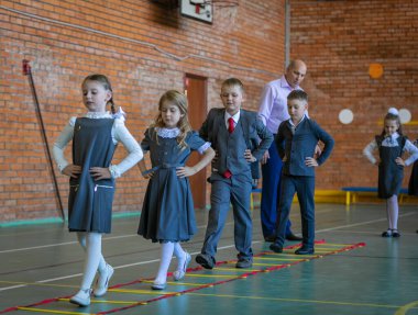 Spor salonundaki ilk beden eğitimi dersinde birinci sınıflar. Öğretmen öğrencilere bir görev verir. Moskova, Rusya, 2 Eylül 2019