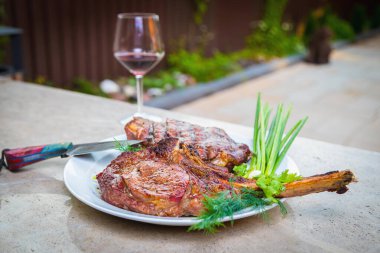 Beyaz tabakta baharatlı kızarmış et. Akşam yemeği için fırında et ve bir bardak kırmızı şarap. Yakın plan.