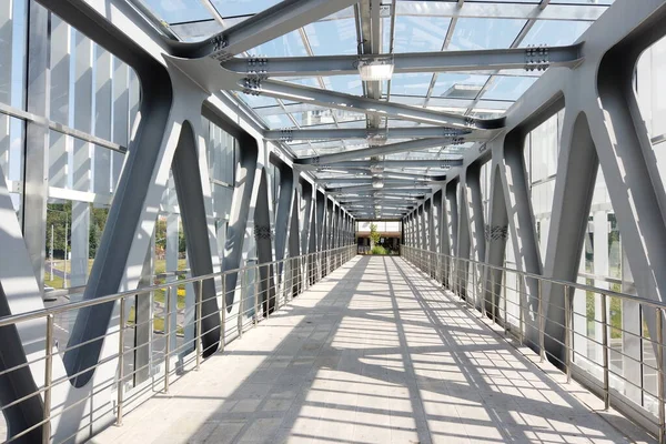 Glass pedestrian bridge with metal beams inside. Perspective perspective. Inside view.