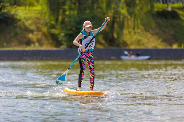 Un niño nada en una tabla de surf, empujando con una pala. Paddleboarding. —  Fotos de Stock