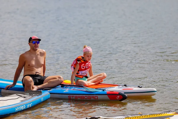 Un niño nada en una tabla de surf, empujando con una pala. Paddleboarding. —  Fotos de Stock