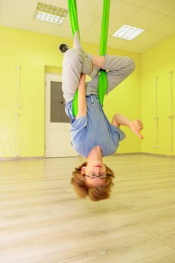 Çocuk salonda bir hamakta yoga yapıyor..