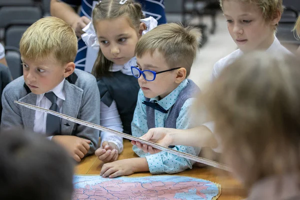 На уроці першокласник з окулярами розглядає карту. 1 вересня. Школа. — стокове фото