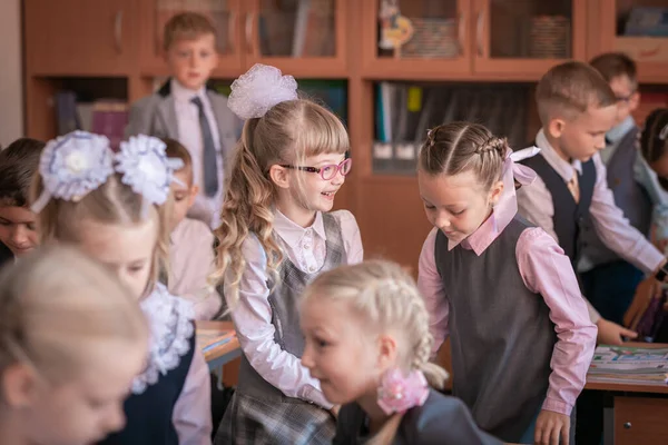 Перший клас стоїть за столом і відповідає на запитання вчителів.. Стокове Фото