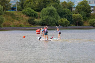 Bir çocuk sörf tahtasının üzerinde yüzüyor, kürekle itiyor. Paddleboard.