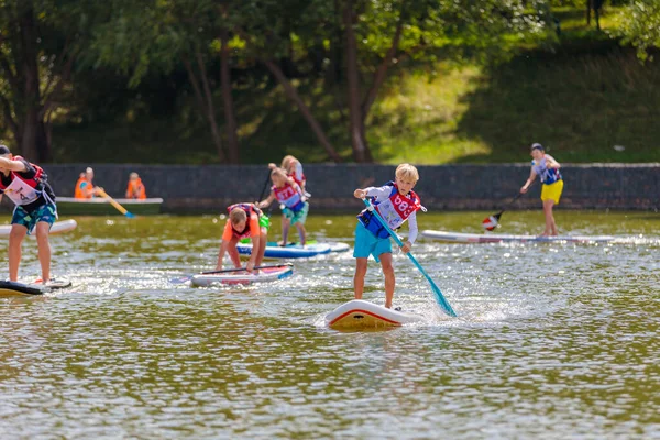 Un niño nada en una tabla de surf, empujando con una pala. Paddleboarding. —  Fotos de Stock