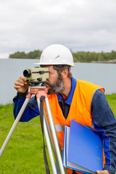 Mužský inženýr pracuje s optickou úrovní na místě. — Stock fotografie