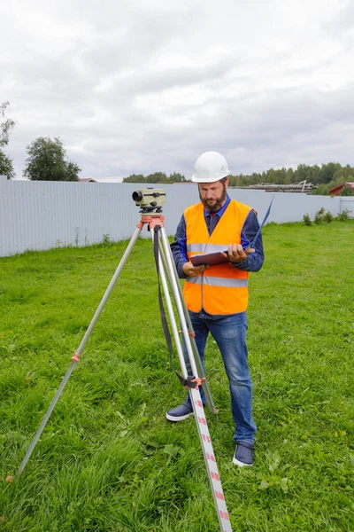 Stavební inženýr zapisuje hodnoty optické úrovně na kus papíru ve složce.. — Stock fotografie