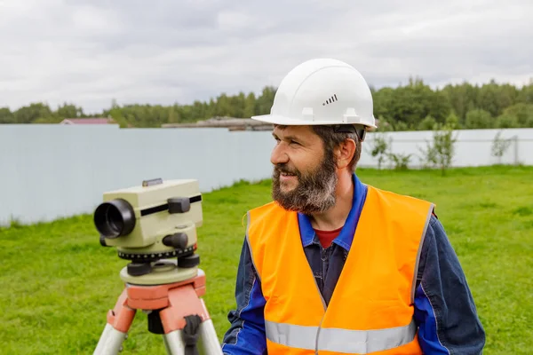 Mužský inženýr pracuje s optickou úrovní na místě. — Stock fotografie