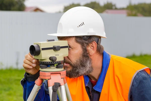 Um engenheiro masculino trabalha com o nível óptico no local. — Fotografia de Stock