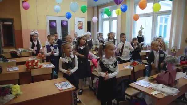 教室の学校の1年生は先生と一緒に陽気なダンスを踊る 子供たちは教室で踊っている モスクワロシア2021年9月1日 — ストック動画