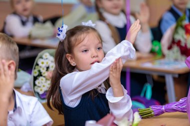 Birinci sınıf öğrencisi derste elini kaldırır ve bir cevap vermek ister. Okulda, 1 Eylül bilgi günüdür. Moskova, Rusya, 1 Eylül 2021