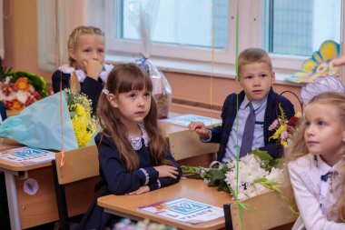 1 Eylül 'de çocuklar sınıfta masalarında otururlar. Birinci sınıflar ilk derste öğretmeni dikkatle dinlerler. Moskova, Rusya, Eylül 2021