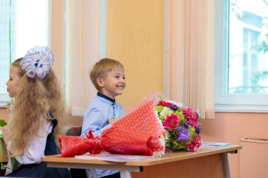 1 Eylül 'de çocuklar sınıfta masalarında otururlar. Birinci sınıflar ilk derste öğretmeni dikkatle dinlerler. Moskova, Rusya, Eylül 2021