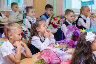 1 Eylül 'de çocuklar sınıfta masalarında otururlar. Birinci sınıflar ilk derste öğretmeni dikkatle dinlerler. Moskova, Rusya, Eylül 2021