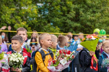 Birinci sınıflar 1 Eylül 'de buketlerle yürürler. Çocuklar okula gidiyor, birinci sınıflar çiçeklerle. Okul eğitimi konsepti. Moskova, Rusya, 1 Eylül 2021