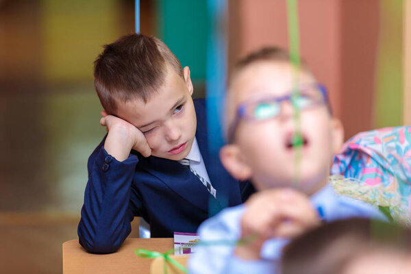 On September 1, children sit at their desks in class. First graders listen carefully to the teacher in the first lesson. Moscow, Russia, September 2021