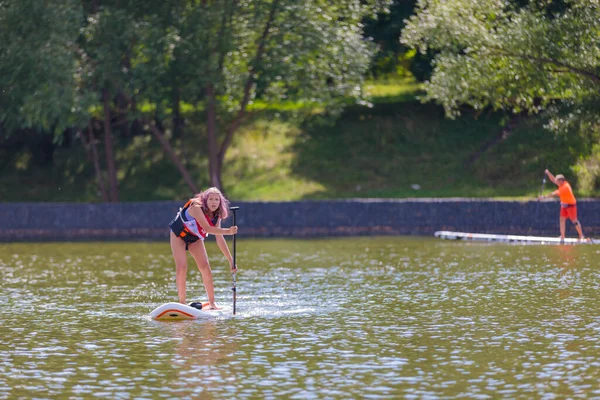 子供はサーフボードで泳ぎ パドルでプッシュします パドルボーディング ロシアゼレノグラード14 8月2021 — ストック写真
