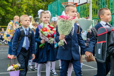 Birinci sınıflar 1 Eylül 'de buketlerle yürürler. Çocuklar okula gidiyor, birinci sınıflar çiçeklerle. Okul eğitimi konsepti. Moskova, Rusya, 1 Eylül 2021