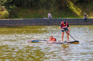 Bir çocuk sörf tahtasının üzerinde yüzüyor, kürekle itiyor. Sörf tahtası. Rusya Zelenograd 14 Ağustos 2021