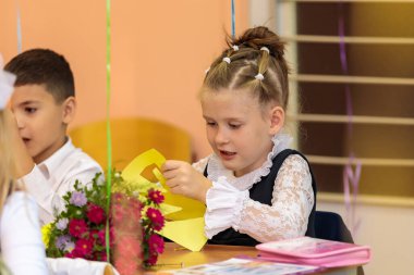 Dersteki birinci sınıflar kağıt üzerindeki başvuruların rakamlarını kestiler. Okul, Bilgi Günü. Moskova, Rusya, 1 Eylül 2021