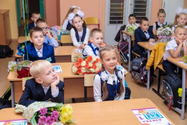 1 Eylül 'de çocuklar sınıfta masalarında otururlar. Birinci sınıflar ilk derste öğretmeni dikkatle dinlerler. Moskova, Rusya, Eylül 2021