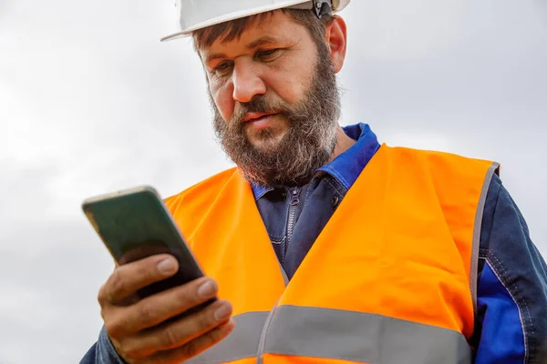 Stavební Inženýr Podívá Mobilní Telefon Vousatý Muž Hledá Informace Svém — Stock fotografie