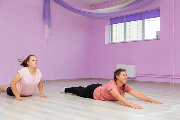 Girl dance instructor shows the elements of the number to another girl. Dance training.