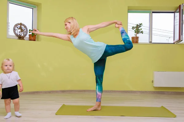 Mom and baby are doing yoga in the hall.