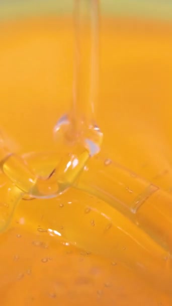 Naturlig genomskinlig honung rinner långsamt in i koppen. Honung häller ur en sked, bildar ringar. — Stockvideo