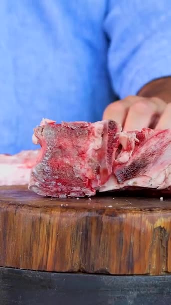 한 남자가 한 블록에서 칼로 날고기를 씹는다. 도마 위에 신선 한 고기를 얹는다. 클로즈업 — 비디오