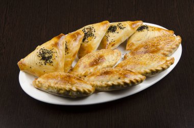 Etli turtalar, samsa, samsa, geleneksel Asya yemekleri beyaz tabakta, ahşap arka planda.
