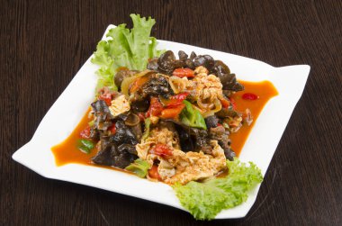 Baharatlı kızarmış tavuk ve soslu salata, sebzeli, geleneksel Asya mutfağı, ahşap arka planda beyaz bir tabakta.