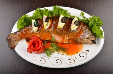 Limon dilimleri ve zeytinli kızarmış balık.