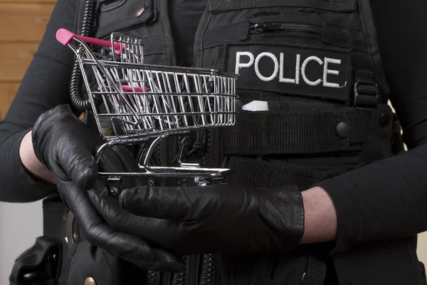 Concepto de levantamiento de tiendas Oficial de policía sosteniendo un pequeño carro de compras —  Fotos de Stock