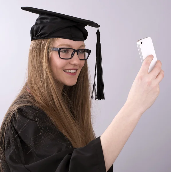 Graduado tomando una foto selfie usando un teléfono móvil — Foto de Stock