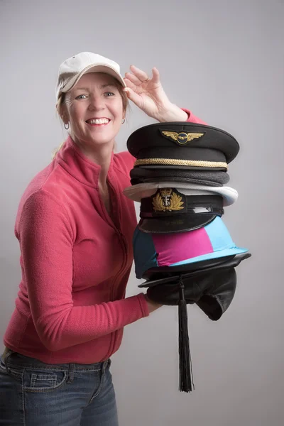 Woman holding a variety of hats and caps from various professions