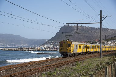 Costal line passenger train passing Kalk Bay in the Western cape South Africa clipart