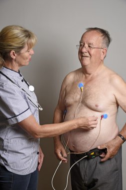 Cardiologist installing a ECG monitor onto a patient's chest clipart
