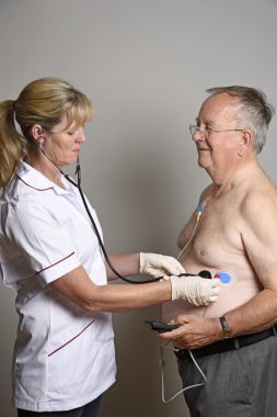 Kardiyolog yaşlı bir erkek hasta kalbi steteskop ile kontrol