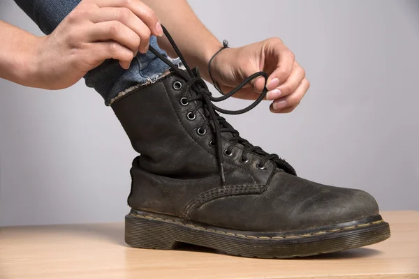 Atar cordones en un lazo en un par de botas negras — Foto de Stock