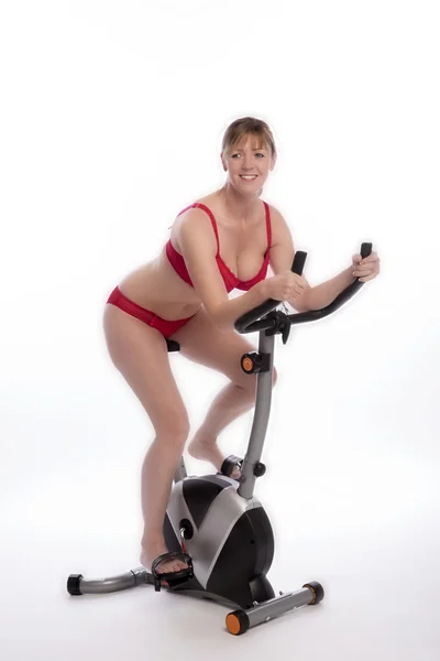 WOMAN WEARING RED UNDERWEAR  RIDING AN EXERCISE BIKE — Stock Photo, Image